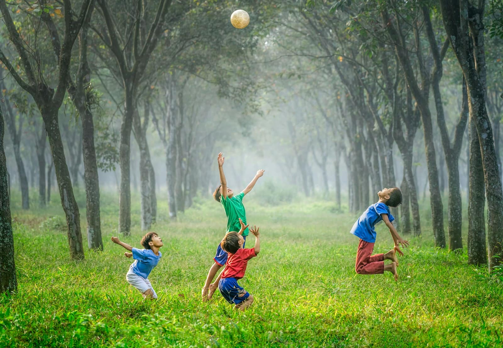 School-age kids playing outdoors with a ball at summer camp